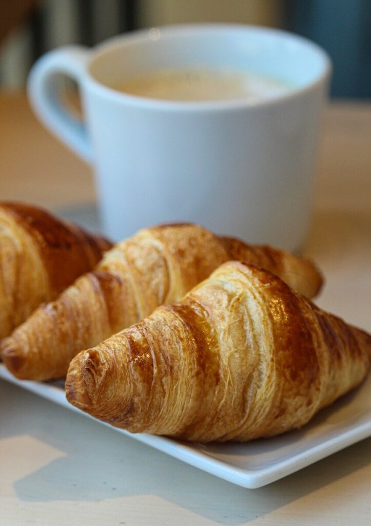 a white plate topped with croissants next to a cup of coffee